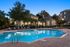 Luxurious apartment complex featuring a serene swimming pool surrounded by lush greenery and elegant architecture, perfect for relaxation and leisure.