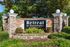 Welcoming stone entrance sign for Retreat at Sweetwater Apartments accentuated by lush green landscaping.