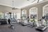 Bright, modern fitness center featuring various exercise machines, free weights, and large windows with garden views.