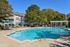 Inviting apartment complex showcasing a sparkling outdoor pool surrounded by lush greenery and stylish lounge chairs, perfect for relaxation and leisure.
