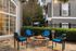 Inviting outdoor patio with a stone fire pit surrounded by four blue-cushioned chairs, perfect for cozy gatherings.