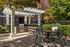 Charming outdoor patio with a stylish pergola, featuring a built-in grill and cozy dining set, perfect for al fresco gatherings amid lush greenery.