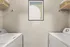 Modern laundry room with sleek washer and dryer, stylish abstract wall art, and practical shelving baskets for organized storage.