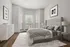 Modern bedroom with elegant grey tones, featuring a chic upholstered bed, textured bedding, and abundant natural light from large windows.