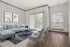 Bright and modern living room with sleek gray sectional, stylish armchairs, and large windows for abundant natural light.