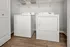 Modern laundry room with high-efficiency washer and dryer on elegant wood flooring.