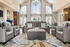 Elegant living room with high ceilings, large arched windows, and modern gray leather seating, offering a luxurious and inviting space bathed in natural light.
