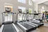 Modern fitness center with treadmills overlooking a scenic view, featuring bright windows and vibrant exercise equipment.