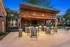 Chic outdoor patio space featuring a modern grill, shaded seating area with fans, and rustic wooden accents, perfect for evening gatherings.