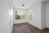 Bright and airy room with elegant wood flooring, large windows, and a modern ceiling fan, perfect for a cozy home setting.
