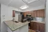Modern kitchen with granite countertops, stainless steel appliances, and dark wood cabinetry, featuring a chic tile backsplash and ambient lighting.