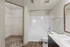 Modern bathroom with sleek white tiles, a spacious bathtub, and an adjoining walk-in closet with ample shelving.