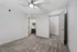 Inviting bedroom showcasing plush carpet and modern ceiling fan, leading to a well-appointed bathroom with stylish cabinetry.
