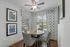 Charming dining nook with round wooden table, patterned chairs, and scenic window view.