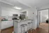 Modern kitchen with sleek stainless steel appliances, granite countertops, and stylish bar seating, leading to a cozy living space.