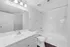 Pristine bathroom showcasing modern white fixtures, sleek cabinetry, and a clean, bright aesthetic with stylish lighting.