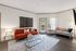 Inviting living room featuring a chic orange sofa, elegant art piece, and abundant natural light from large windows.