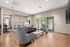 Modern business center lounge with chic teal armchairs, sleek leather sofa, and stylish glass wall partition.