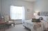 Bright, inviting bedroom featuring plush bed, elegant armchair, and ample natural light from large window.