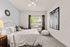 Inviting bedroom with plush carpet, elegant wall art, and a large window allowing natural light to illuminate the serene space.