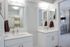Elegant bathroom featuring double vanities with sleek white countertops, contemporary mirrors, and modern lighting in a stylish apartment.