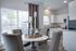 Bright and elegant dining area with a contemporary round table and tufted chairs, seamlessly connected to a modern kitchen featuring sleek cabinetry and stainless steel appliances, offering a perfect blend of style and functionality.