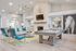 Elegant living room featuring a stylish pool table, cozy seating with vibrant blue accents, and a modern fireplace under a light-filled vaulted ceiling.