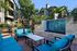 Inviting outdoor seating area with vibrant blue cushions beside a serene mosaic water feature, surrounded by lush greenery in a modern apartment setting.