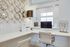 Modern home office with sleek white desk, stylish circular wall art, and a large window illuminating the space.