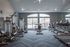 Modern fitness center with state-of-the-art gym equipment, including treadmills, exercise bikes, and weight machines in a bright, spacious room with large windows.