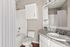 Bright and modern bathroom with a granite countertop, elegant white cabinetry, and a relaxing bathtub.