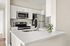 Modern kitchen featuring sleek stainless steel appliances, elegant white cabinetry, and a stylish countertop with a vase of greenery.