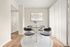 Modern dining area featuring a sleek glass table with four stylish chairs, complemented by natural light streaming through vertical blinds and elegant wall art.