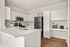 Chic modern kitchen featuring pristine white cabinetry, sleek stainless steel appliances, and elegant wood flooring.