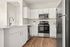 Modern kitchen with sleek stainless steel appliances, elegant white cabinetry, and warm wood flooring, epitomizing contemporary style.