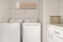 Elegant laundry room featuring sleek modern appliances, abundant storage, and stylish woven baskets.