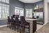 Chic modern kitchen with mosaic tile island, elegant bar stools, and sleek stainless steel appliances, bathed in natural light.