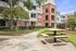 Charming apartment complex with red brick and gray siding, featuring a scenic outdoor area with a picnic table and lush greenery.