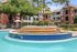 Inviting apartment complex with a sparkling tiered fountain, surrounded by lush greenery and elegant brick architecture.