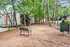 Charming community view with inviting outdoor seating amidst lush trees and modern apartment buildings, perfect for relaxation and nature lovers.