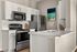 Modern kitchen with sleek stainless steel appliances, white cabinetry, and stylish backsplash, offering a bright and inviting culinary space.