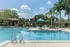 Inviting outdoor pool area with lush landscaping, cozy seating under a blue umbrella, and clear skies promising relaxation and leisure.