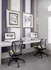 Modern workspace with dual computer stations featuring sleek chairs and artistic wall decor, ideal for productivity and creativity.