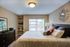 Inviting bedroom with elegant decor, plush bedding, and natural light from a large window, creating a cozy and relaxing atmosphere.