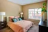 Inviting bedroom featuring modern decor with vibrant orange bedding, elegant bedside lamps, and a large window offering natural light.
