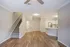 Bright open-concept living space with modern kitchen, elegant wood floors, and cozy carpeted stairway.