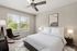 Bright and serene bedroom with a cozy bed, elegant decor, and a soothing view of lush greenery through wide windows.