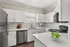 Modern kitchen with sleek white cabinets, stainless steel appliances, and elegant countertop featuring a bowl of fresh green apples.