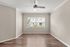 Bright, spacious room with sleek wood flooring, modern ceiling fan, and large window offering scenic neighborhood views.