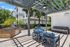 Chic outdoor patio with modern pergola, blue cushioned seating, and a sleek barbecue grill, perfect for entertaining.